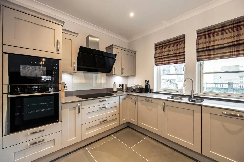 a kitchen with white cabinets and a sink and a microwave at Holly Tree Cottage in Dornoch