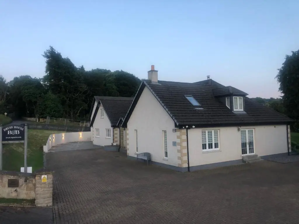 a white house with a black roof and a driveway at Druid Apartment in Inverness
