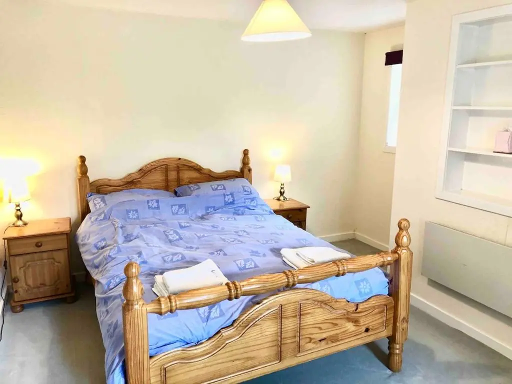 a bedroom with a wooden bed with blue sheets at Canal Side Cottage,on the banks of the Caledonian Canal in Inverness