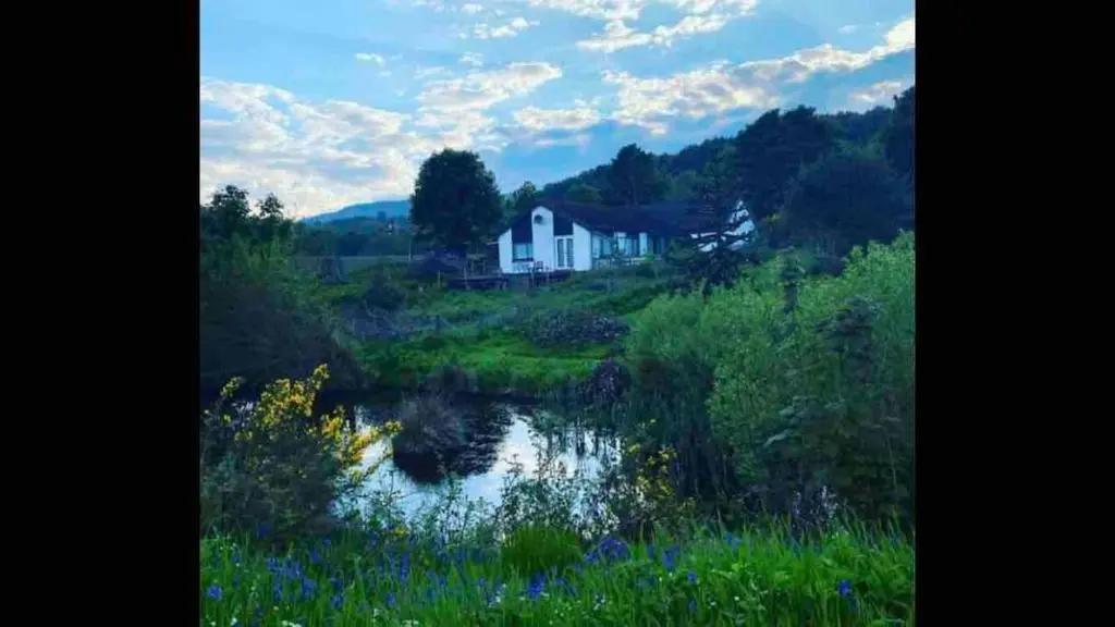 a house sitting on a hill next to a river at Canal Side Cottage,on the banks of the Caledonian Canal in Inverness