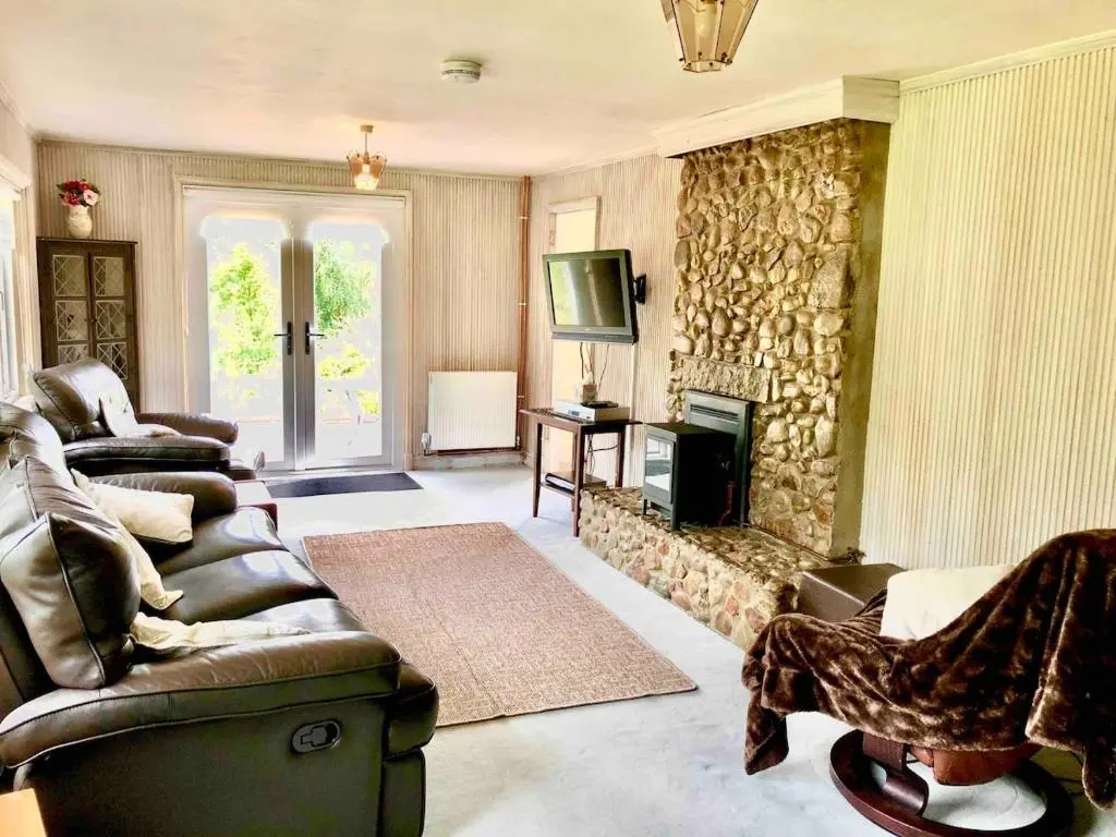 a living room with couches and a stone fireplace at Canal Side Cottage,on the banks of the Caledonian Canal in Inverness