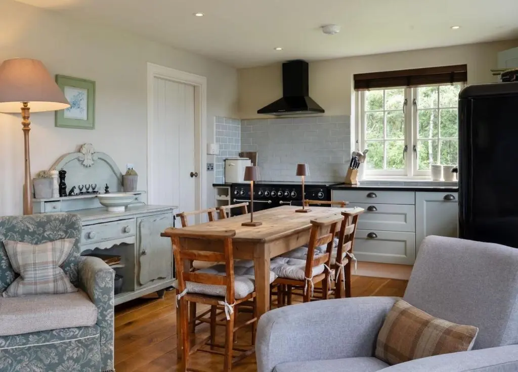 a kitchen with a wooden table and chairs in a room at Brachkashie Cottage, Loch Knockie in Whitebridge