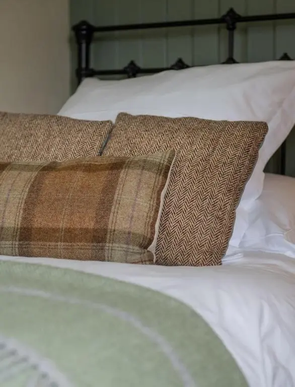 a bed with white sheets and pillows on it at Brachkashie Cottage, Loch Knockie in Whitebridge