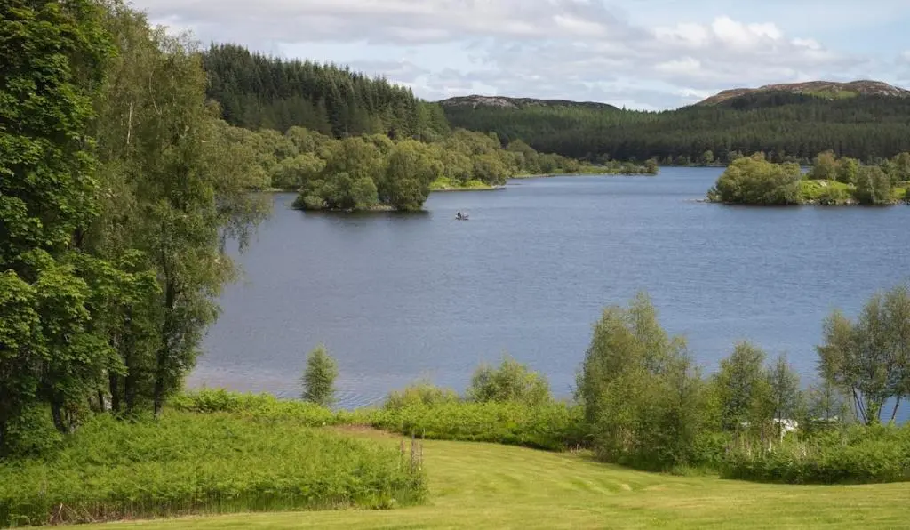 a view of a lake in the middle of a forest at Brachkashie Cottage, Loch Knockie in Whitebridge