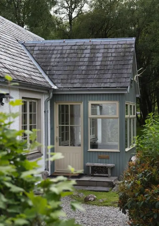a small green house with a bench in front of it at New Brachkashie Cottage in Whitebridge