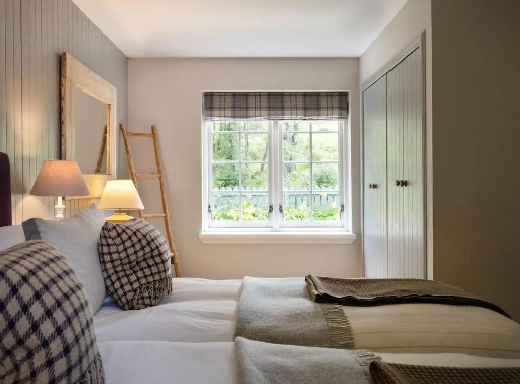 a bedroom with a white bed and a window at New Brachkashie Cottage in Whitebridge
