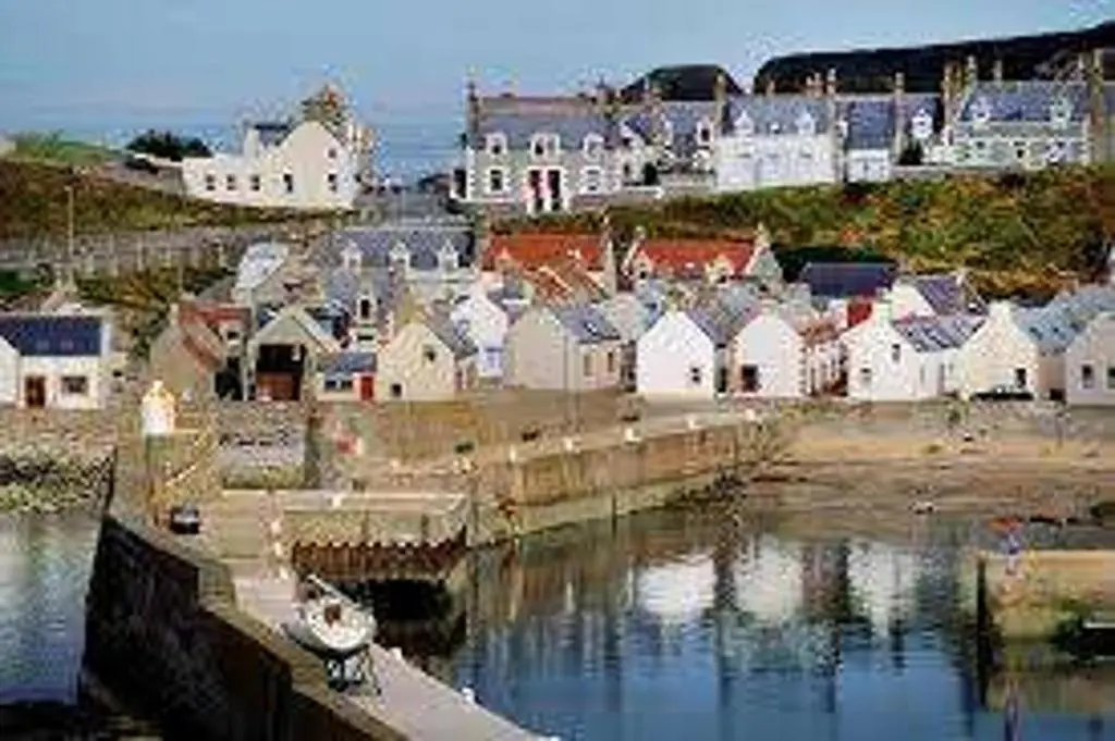a group of houses and a harbor with a boat in the water at Findochty Beach house - Private Garden-BeachFront in Buckie
