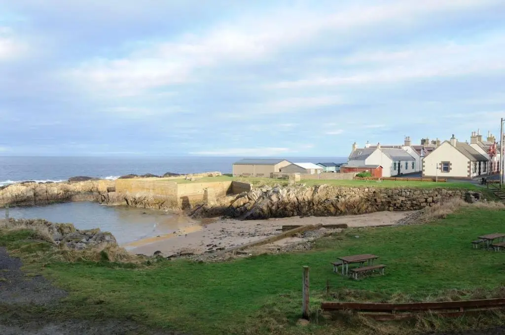 a picnic table on a beach near the ocean at Findochty Beach house - Private Garden-BeachFront in Buckie
