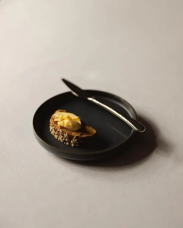 a black plate with a piece of food on a spoon at The Station Hotel in Rothes