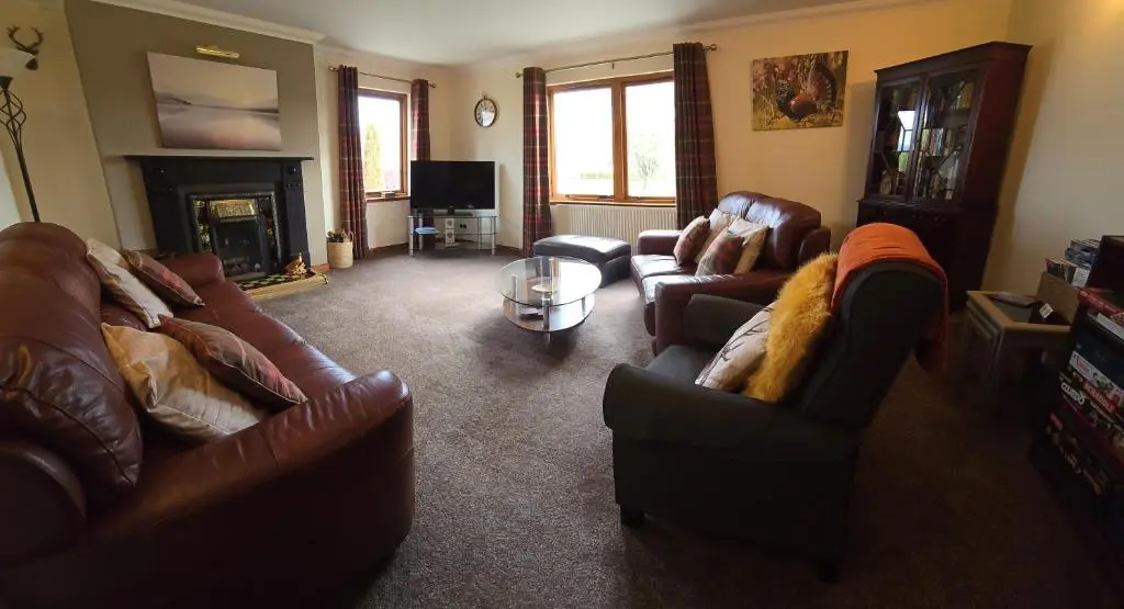 a living room with leather furniture and a fireplace at Dail Daraich in Munlochy