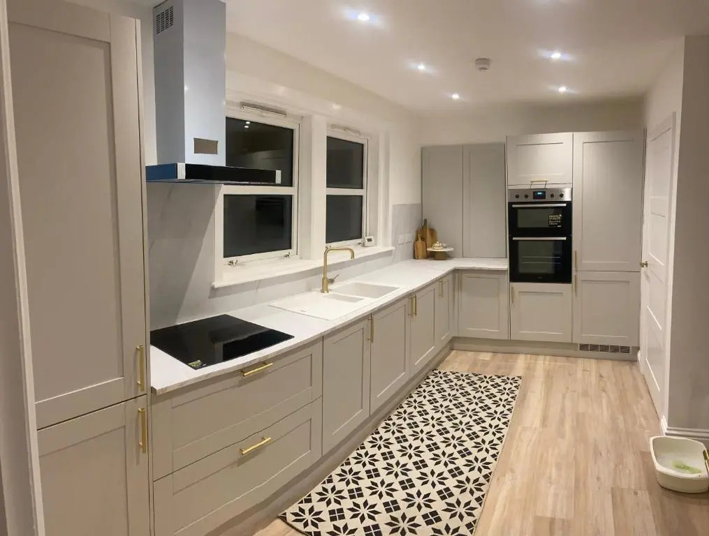 a kitchen with white cabinets and a black and white rug at Halfred House in Wick