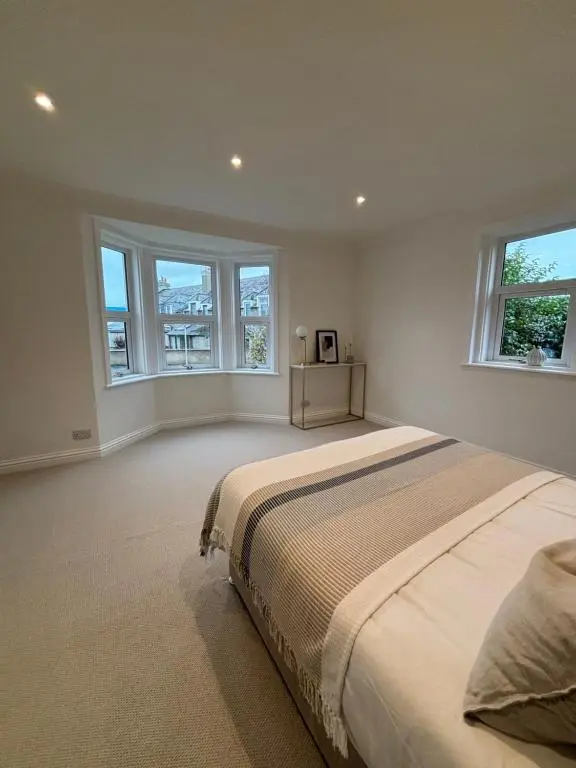 a bedroom with a large bed and two windows at Halfred House in Wick