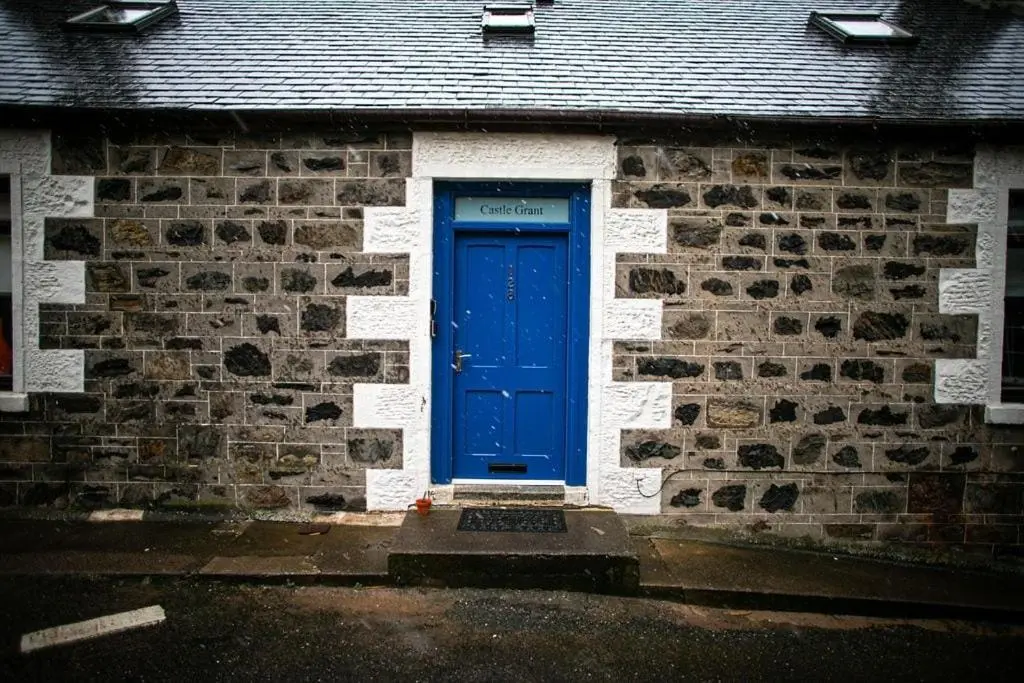 a blue door on the side of a brick building at Castle Grant - 4 Bed Cottage in Gardenstown in Gardenstown