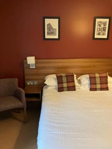 a hotel room with a bed and a chair at Eagle Hotel in Dornoch