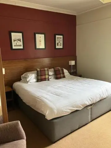 a bedroom with a large bed with red walls at Eagle Hotel in Dornoch