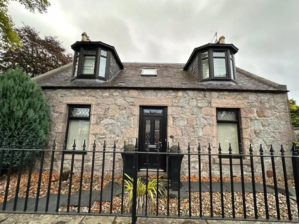 an old stone house with two windows and a fence at 3 Bed Cottage Sleeps 2 with Parking Garden & Wifi in Aberdeen