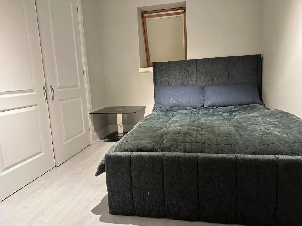 a bedroom with a large bed and a table at 3 Bed Cottage Sleeps 2 with Parking Garden & Wifi in Aberdeen