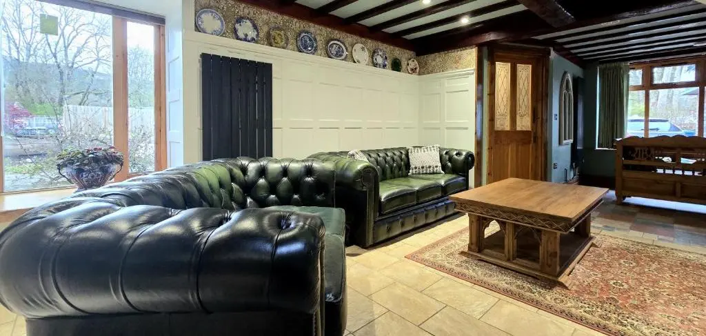 a living room with a leather couch and a table at The Old Stables in Fort Augustus