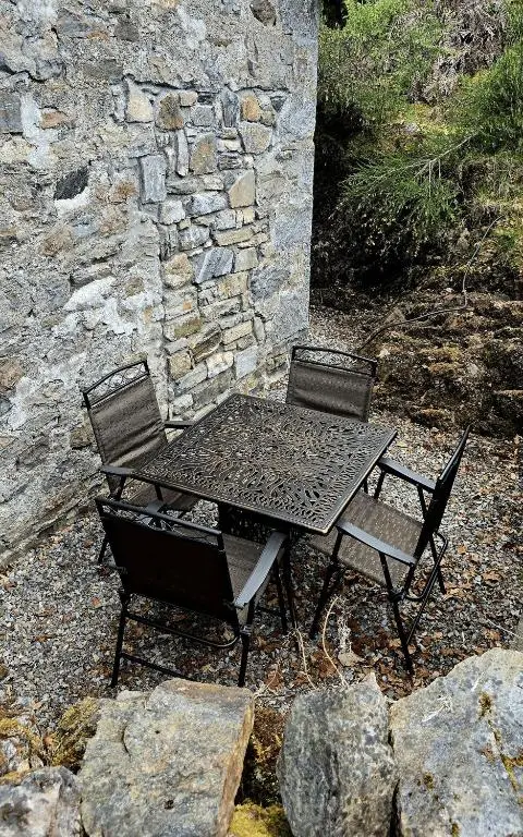 a picnic table and two chairs next to a stone wall at The Old Stables in Fort Augustus