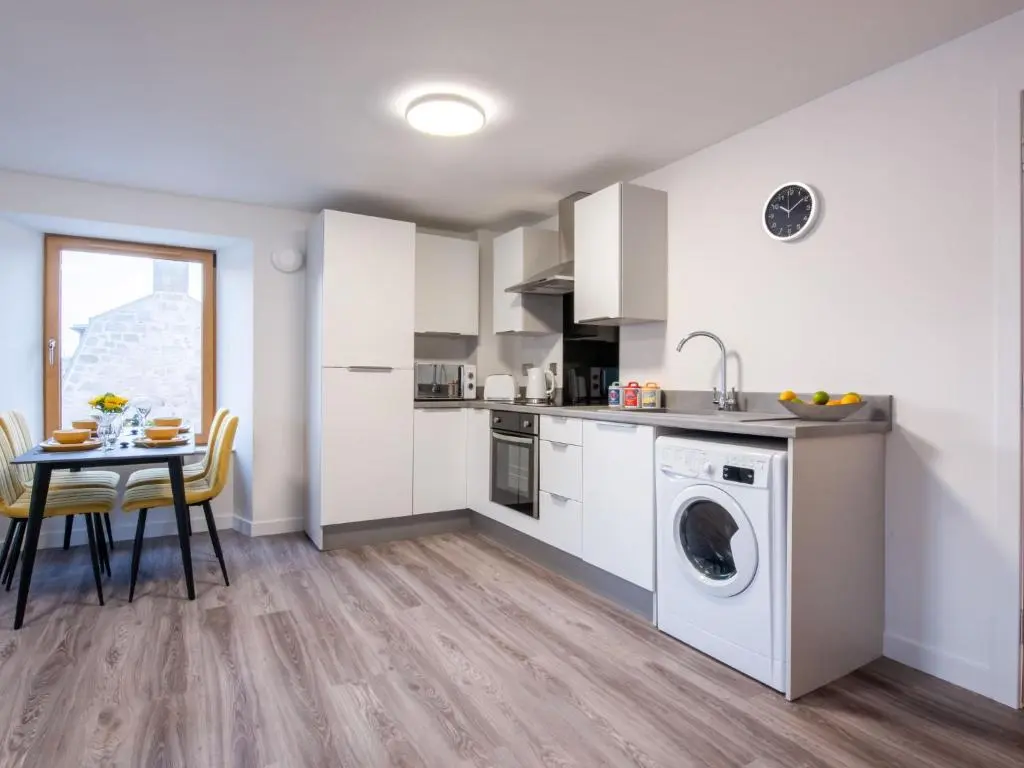 a kitchen with a washing machine and a table at Apartment Harbour Nights Deluxe 7E by Interhome in Lossiemouth
