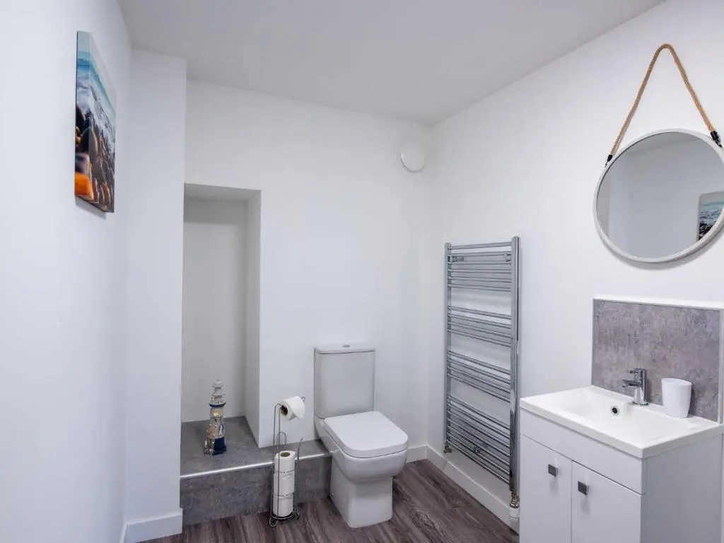 a white bathroom with a toilet and a mirror at Apartment Harbour Nights Deluxe 7F by Interhome in Lossiemouth