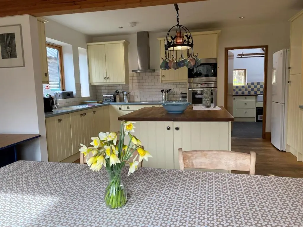 a kitchen with a vase of flowers on a table at Spacious, cosy 6 bedroom house which sleeps 11 in Banchory