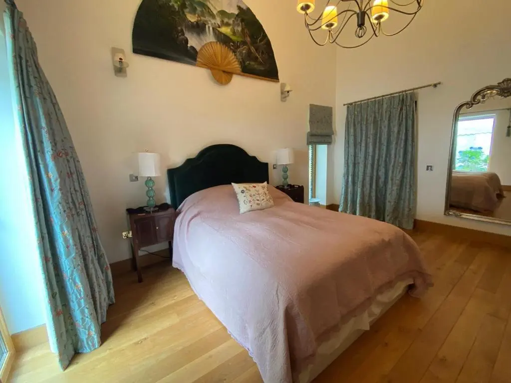 a bedroom with a bed and a chandelier at Spacious, cosy 6 bedroom house which sleeps 11 in Banchory