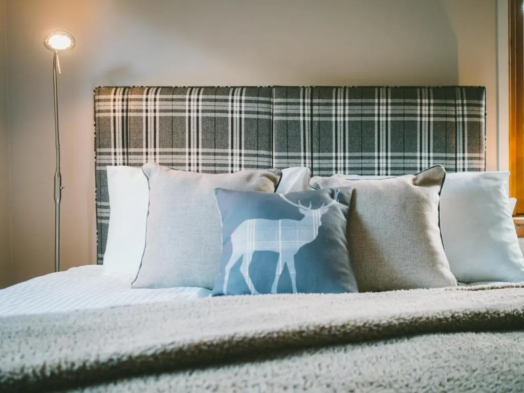a bed with pillows with a deer painted on it at Cairn Eilrig - Seasgair Lodges in Loch Morlich
