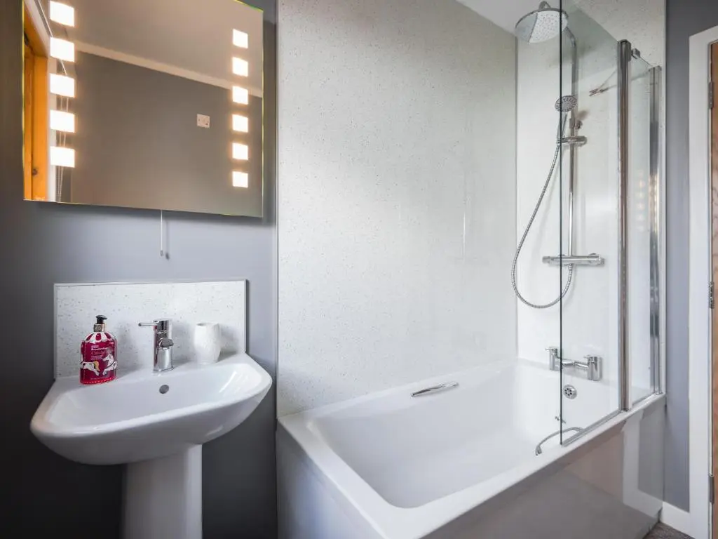 a white bathroom with a sink and a shower at Cairn Eilrig - Seasgair Lodges in Loch Morlich