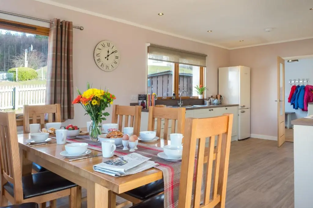 a kitchen and dining room with a table and chairs at Cairn Eilrig - Seasgair Lodges in Loch Morlich
