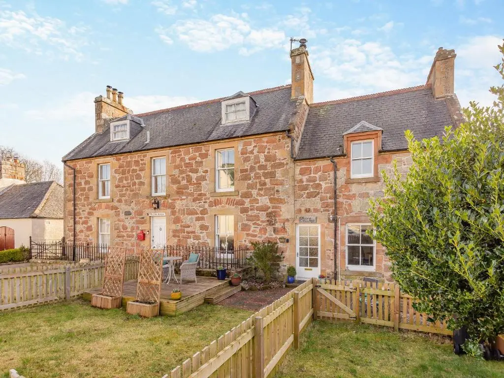 an exterior view of a brick house with a wooden fence at Ord Cottage in Kildary