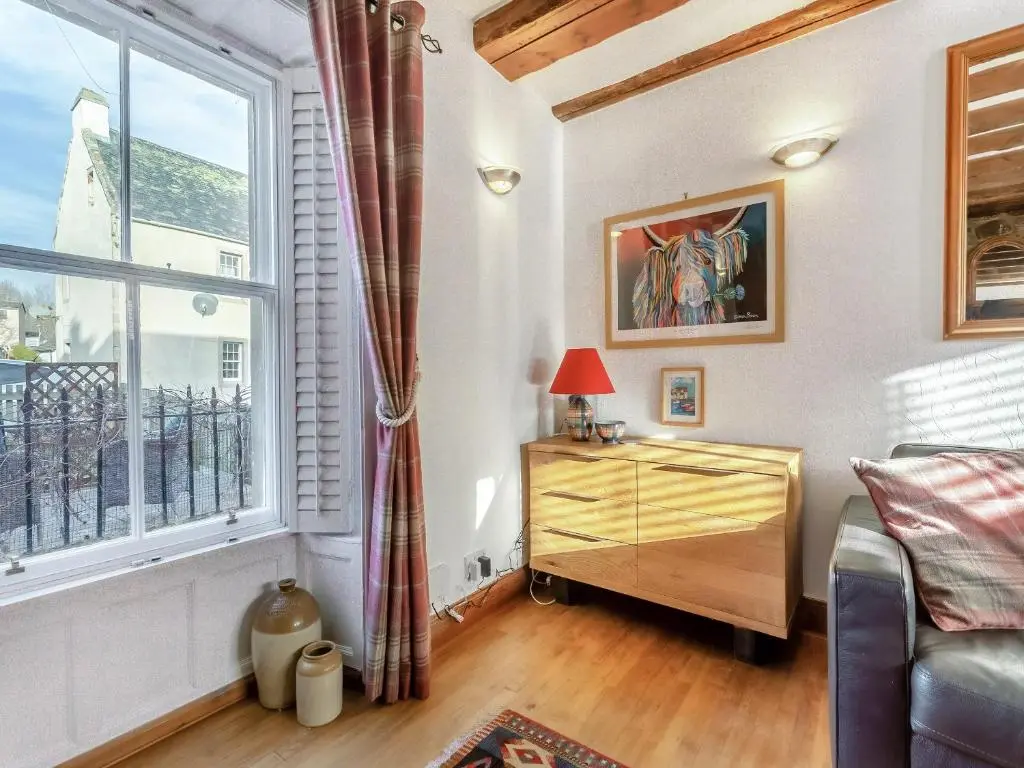 a living room with a bed and a window at Ord Cottage in Kildary