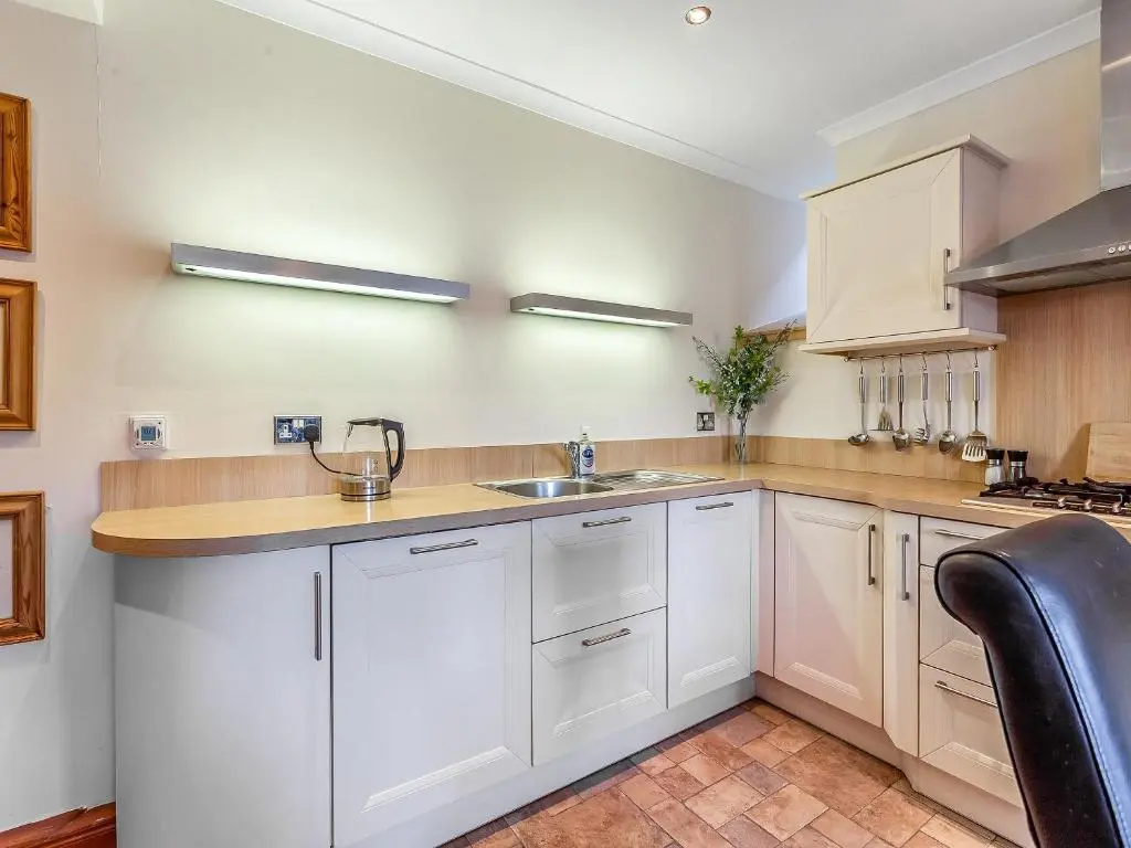 a kitchen with white cabinets and a sink at Ord Cottage in Kildary