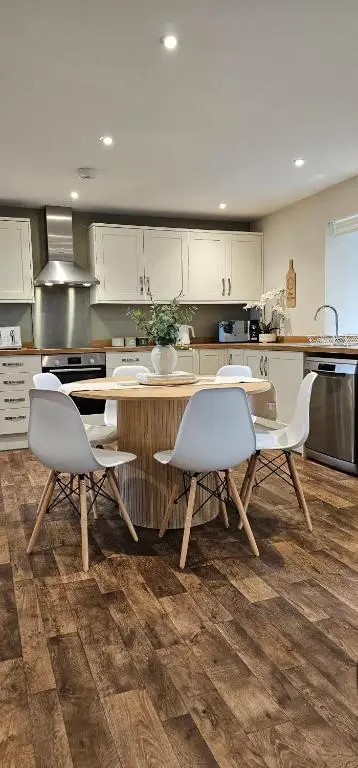 a kitchen with white cabinets and a table and chairs at 3 Bed House near Loch Ness in Inverness