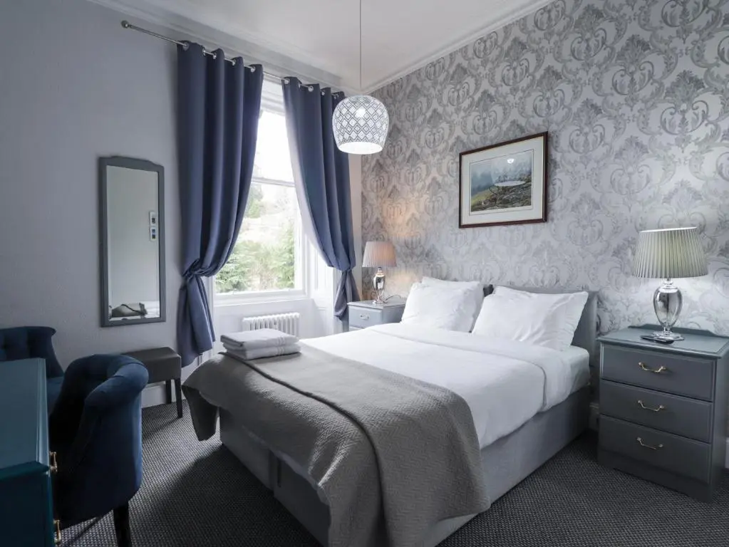 a bedroom with a large bed and a window at Glenspey in Kingussie