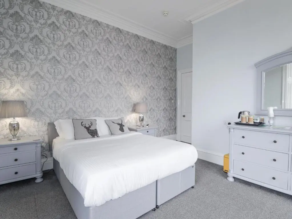 a white bedroom with a white bed and two night stands at Glenspey in Kingussie