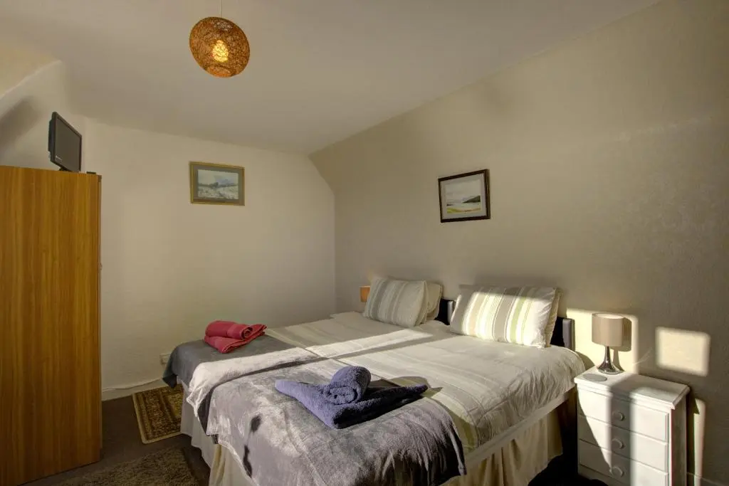 a bedroom with a bed and a tv on the wall at Kavija, Invergordon in Invergordon