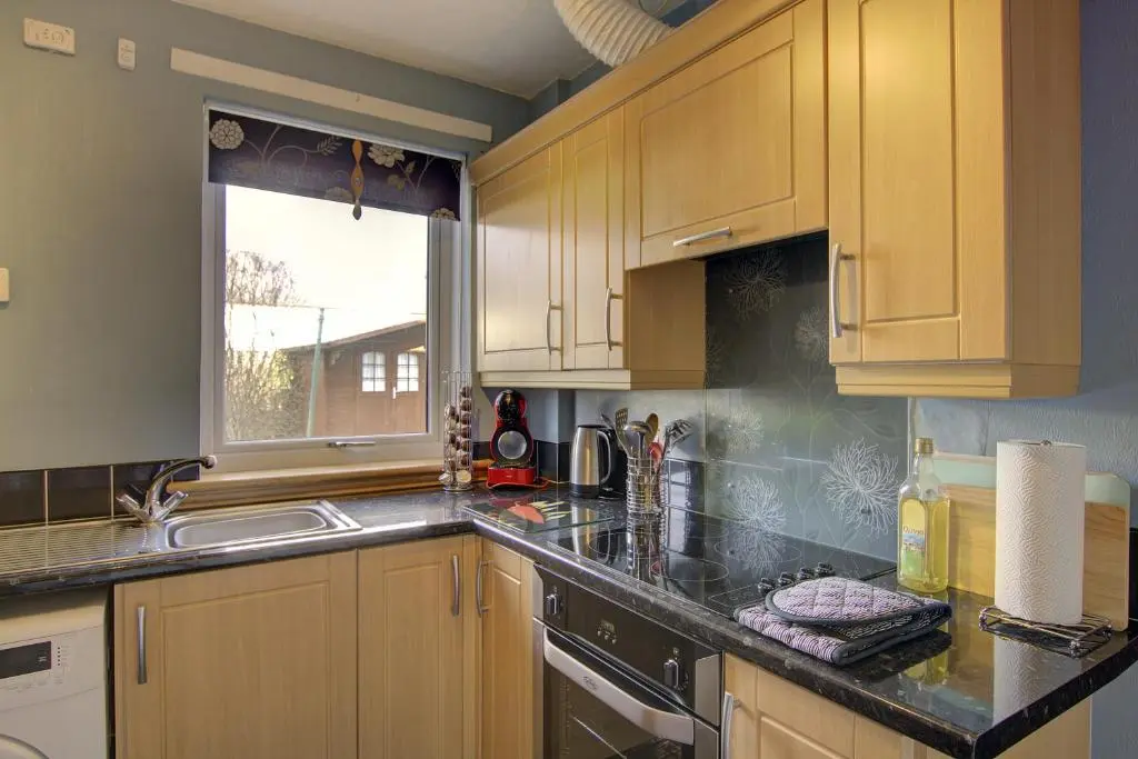 a kitchen with wooden cabinets and a sink and a window at Kavija, Invergordon in Invergordon