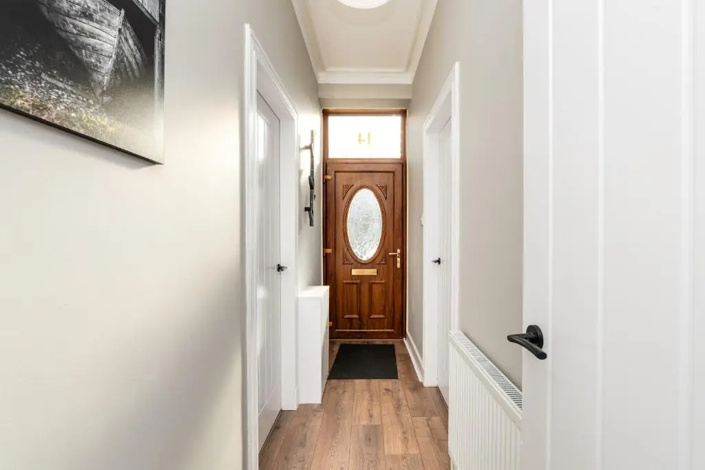 a hallway with white walls and a wooden door at 2 Bedroom Flat - Free Parking - by Holiday Homes in Inverurie