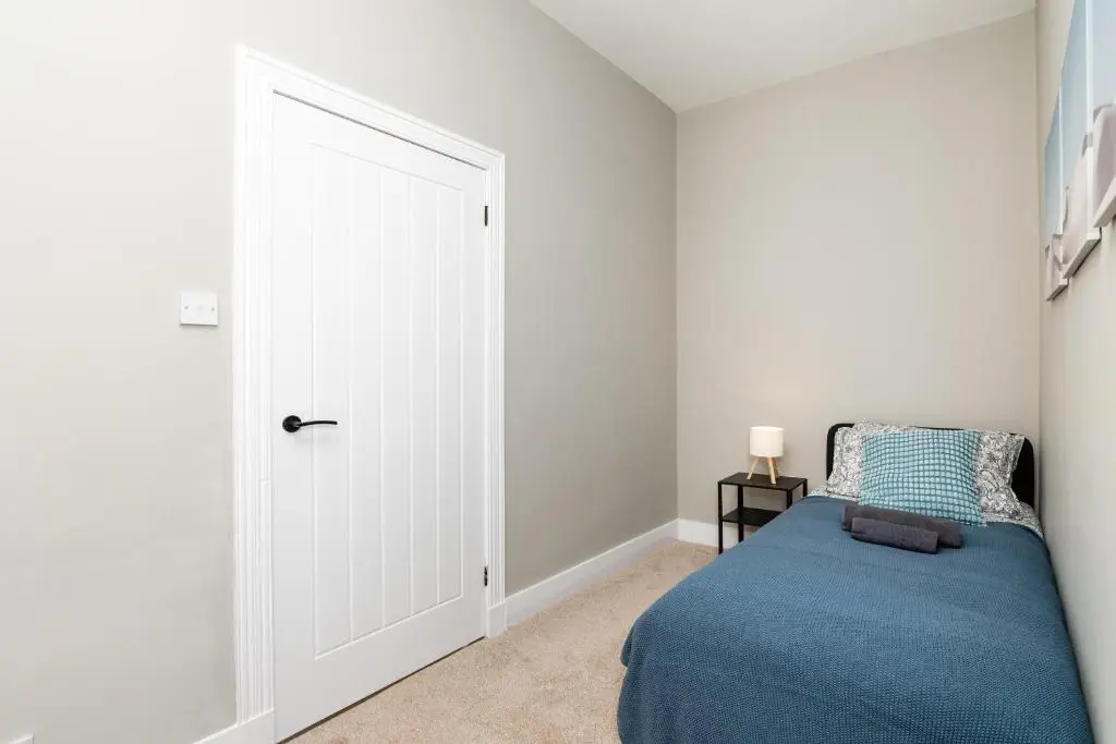 a bedroom with a blue bed and a door at 2 Bedroom Flat - Free Parking - by Holiday Homes in Inverurie