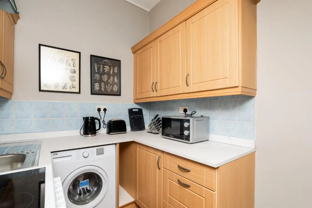 a kitchen with a washing machine and a microwave at 2 Bedroom Flat - Free Parking - by Holiday Homes in Inverurie