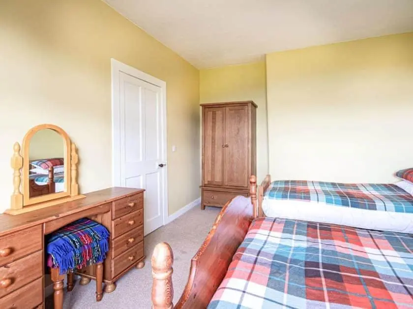 a bedroom with a bed and a dresser and a mirror at Auld House in Brora