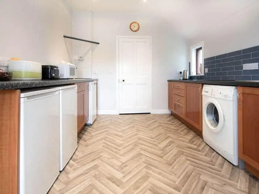 a kitchen with a washer and dryer in a room at Auld House in Brora