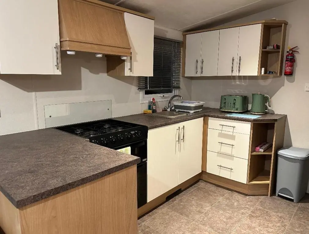 a kitchen with white cabinets and a black stove at Covesea View Silver Sands in Lossiemouth