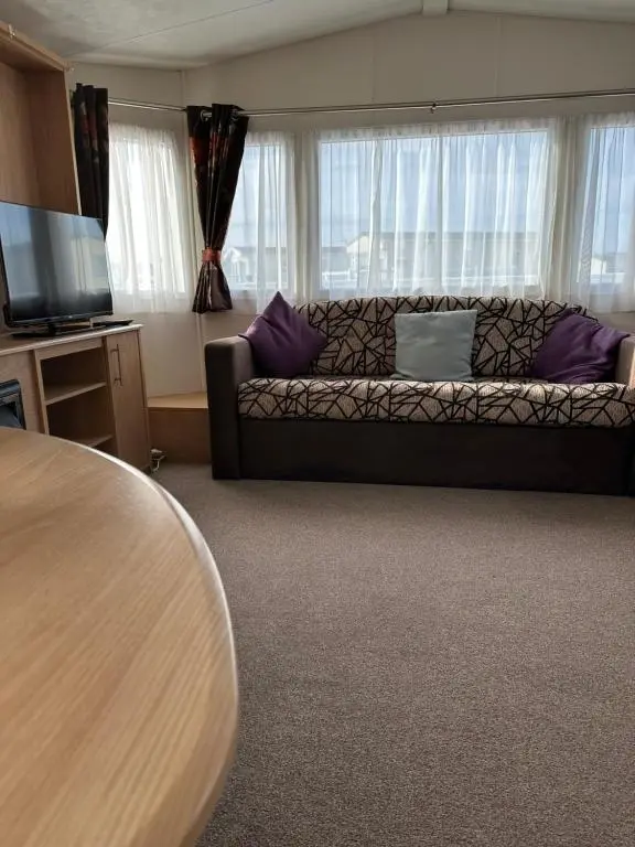 a living room with a couch and a table at Covesea View Silver Sands in Lossiemouth