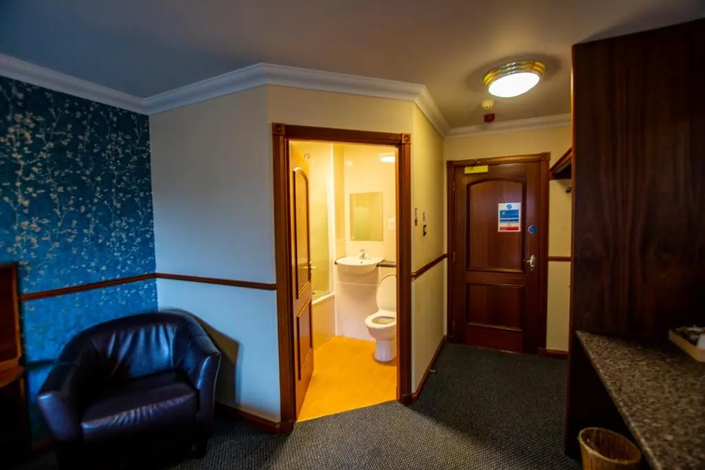 a hotel room with a chair and a bathroom at Findlay's in Fraserburgh
