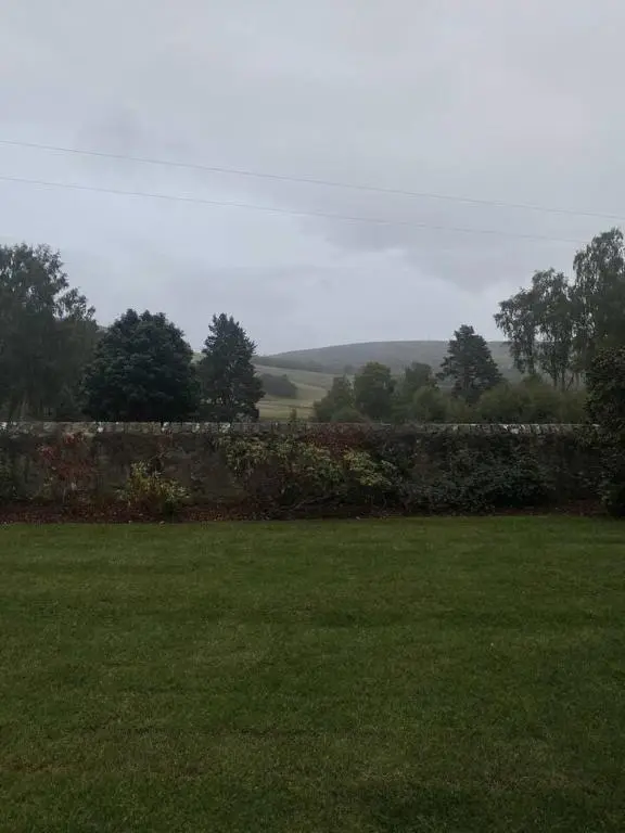 a garden with a stone wall and green grass at Old school - Charming Historic Cottage for Seven in Ballater