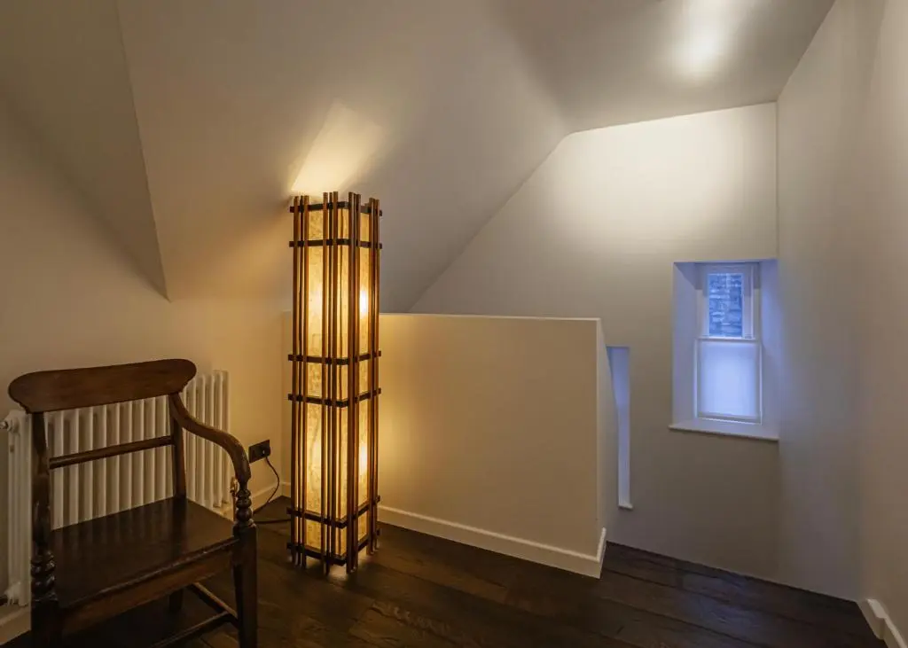 an attic room with a wooden chair and a lamp at Old school - Charming Historic Cottage for Seven in Ballater