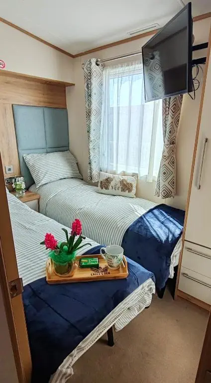 a bedroom with two beds and a tray with flowers on it at Eagle's Den Caravan Holiday Retreat in Lossiemouth