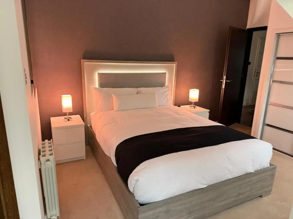 a bedroom with a large white bed with two lamps at Castlefield Penthouse in Inverness